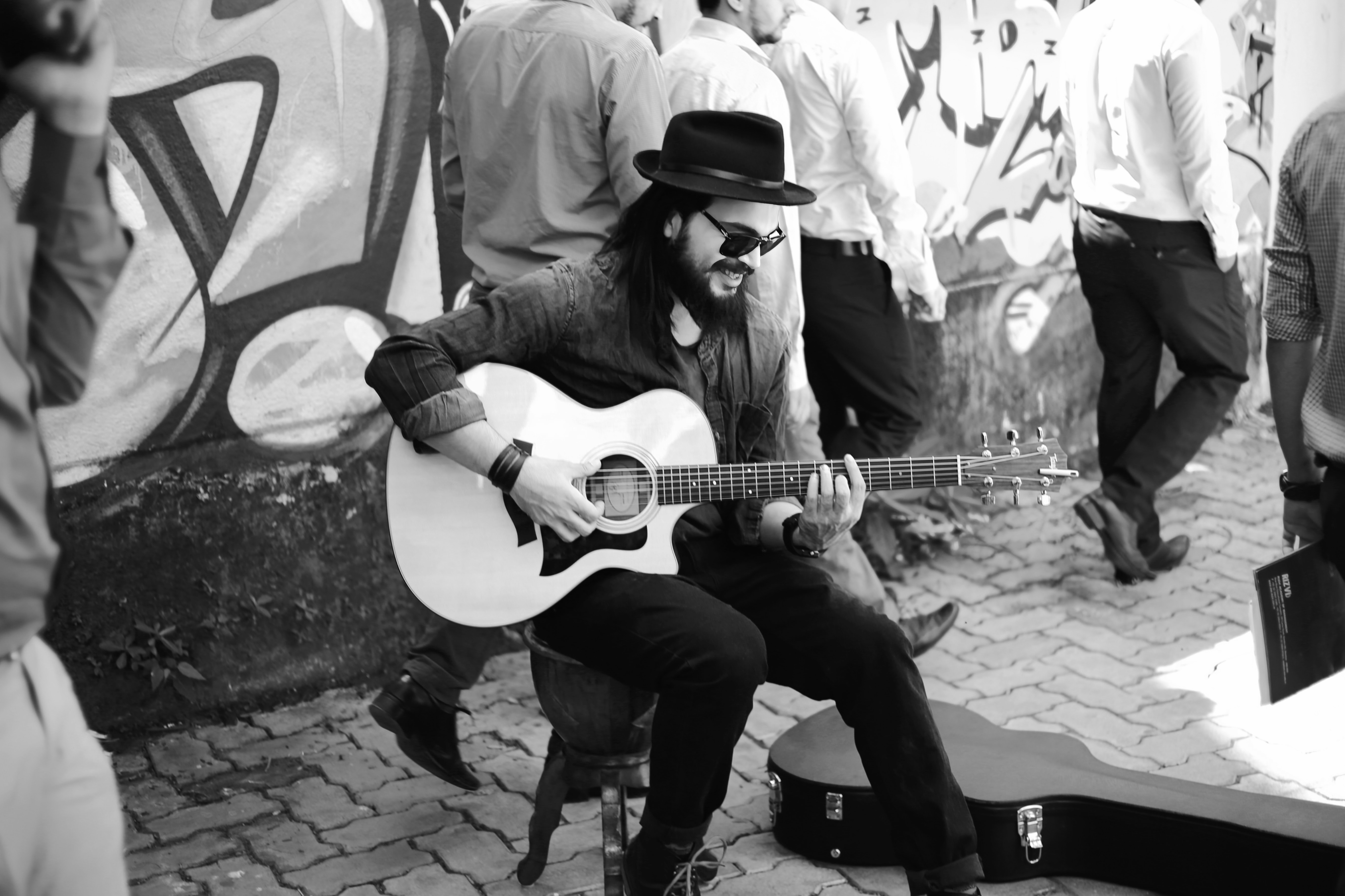 Mumbai-based singer, songwriter, and guitarist Umang Mehta playing an Taylor electric guitar while seated on a in the middle of a bustling street